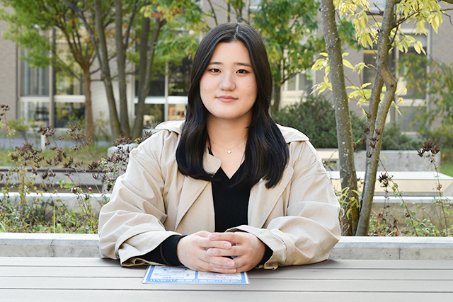 滋賀県のびわこくさつキャンパス内のベンチに座り、今後の目標を語る松本さん