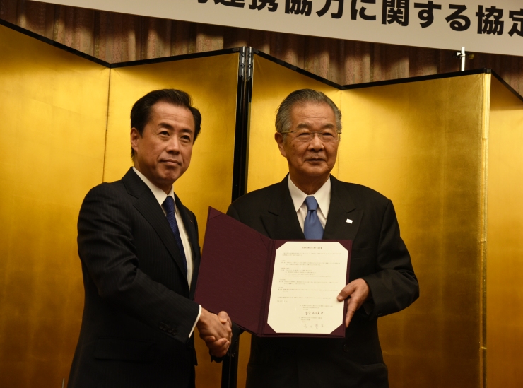 握手を交わす鈴木代表幹事（左）と長田理事長（右）