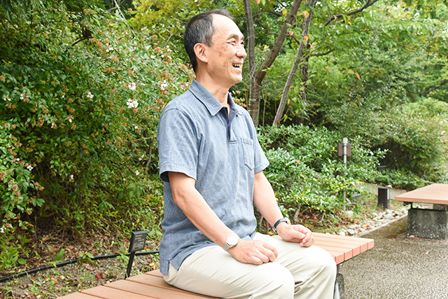 衣笠キャンパスのベンチに座る笑顔の栗川さん