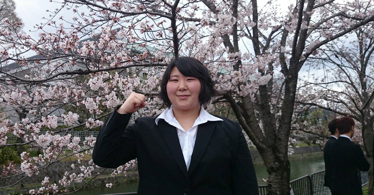 満開の桜の木の下で力強くガッツポーズ