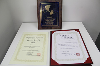 日本植物形態学会 平瀬賞の賞状（写真手前左）と盾（写真奥）、日本細胞生物学会 若手最優秀発表賞の賞状（写真手前右）