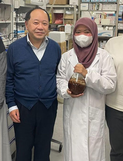 西澤幹雄教授と生薬エキスの入ったフラスコを持つDr. Afiyanti