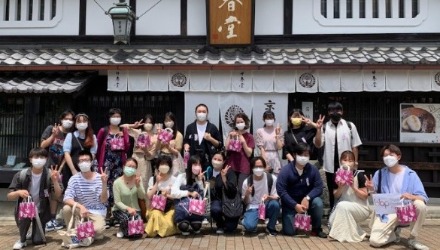 和菓子つくり体験を終えた学生20名が和菓子屋さんの前でポースする