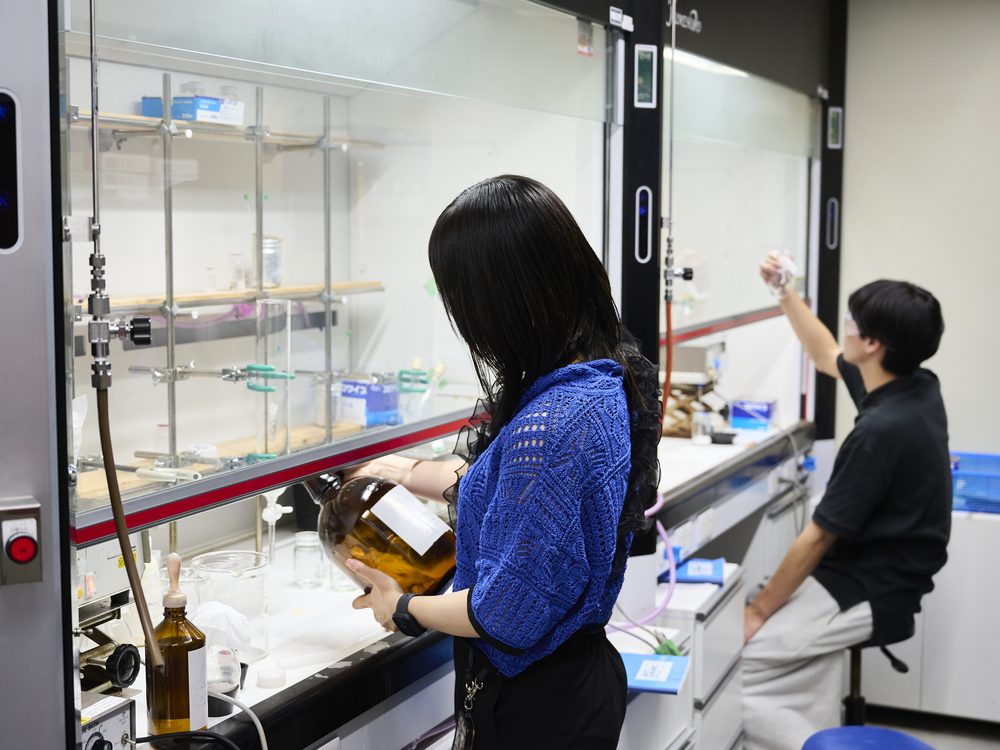 Two students handling glassware in a fume hood