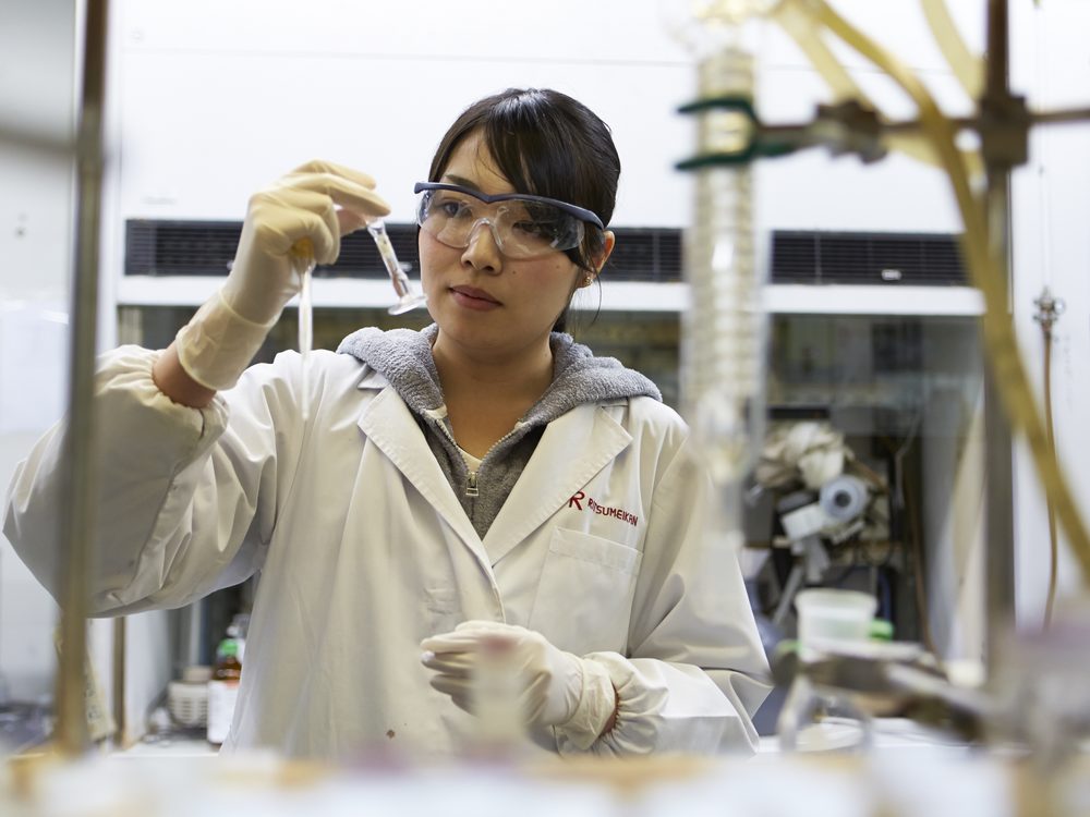 A student in a lab coat handling a sample