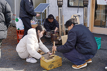 薪を用いて木が持つエネルギーを考える大学生