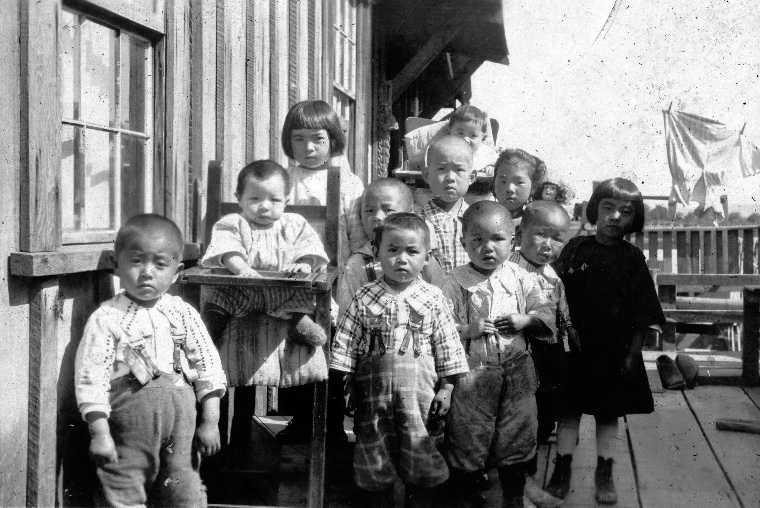 Children belonging to a cannery gather at a Japanese cabin
